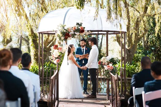 Cropped shot of a handsome young male marriage officiant joining a young couple in marriage outdoors.