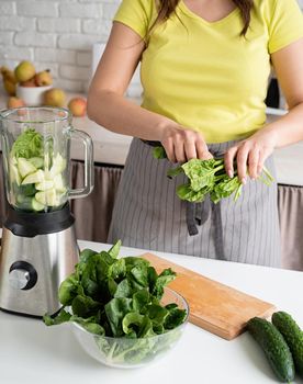 Preparing healthy foods. Healthy eating and dieting. Young brunette woman making green smoothie at home kitchen