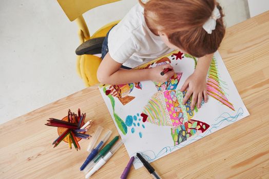 Process of making art. Cute little girl in art school draws her first paintings by pencils and markers.