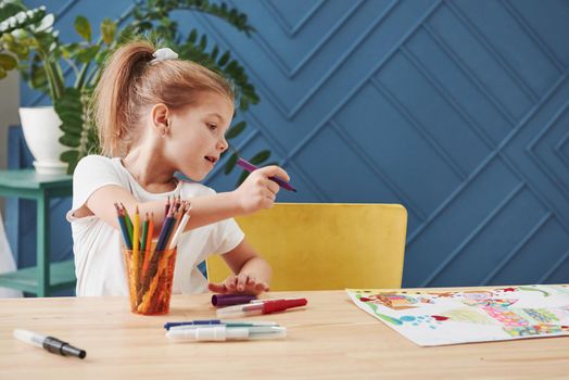 Need to make some corrections. Cute little girl in art school draws her first paintings by pencils and markers.