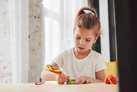 Using stick from artificial candy to make some new stuff. Children playing with colored plasticine on the wooden table at home.