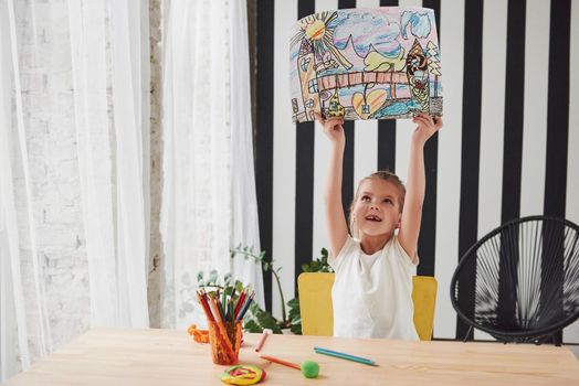 Isn't it beautiful piece of art. Cute little girl in art school shows her first paintings drawn by pencils and markers.