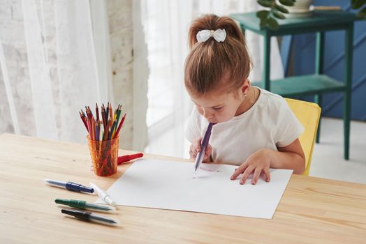 Starting new picture. Cute little girl in art school draws her first paintings by pencils and markers.