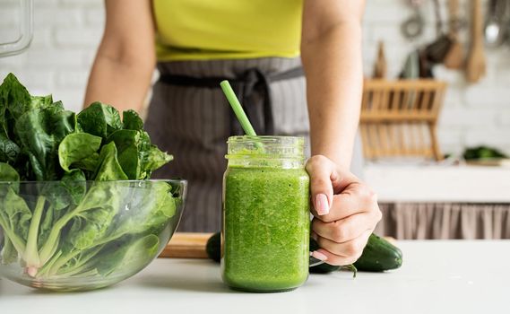 Healthy eating, dieting concept. Close up of a young woman holding a jar of green smoothie