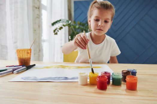 Little girl is drawing by using gouache and brush. Learning in the art class.