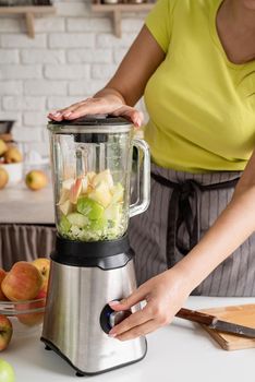 Preparing healthy foods. Healthy eating and dieting. Young brunette woman making banana smoothie at home kitchen