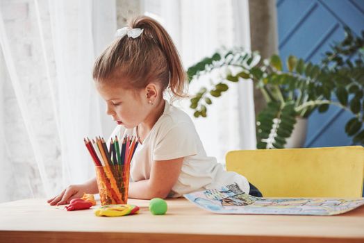 How to busy your kid. Cute little girl in art school draws her first paintings by pencils and markers.