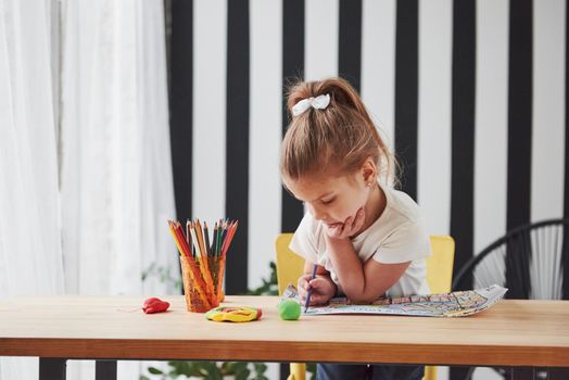 Conception of design and art. Cute little girl in art school draws her first paintings by pencils and markers.