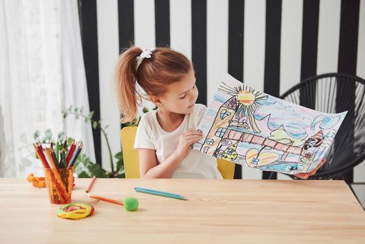 Many colorful pencils was used for this work. Cute little girl in art school shows her first paintings.