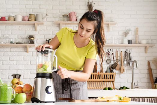 Preparing healthy foods. Healthy eating and dieting. Young brunette woman making banana smoothie at home kitchen