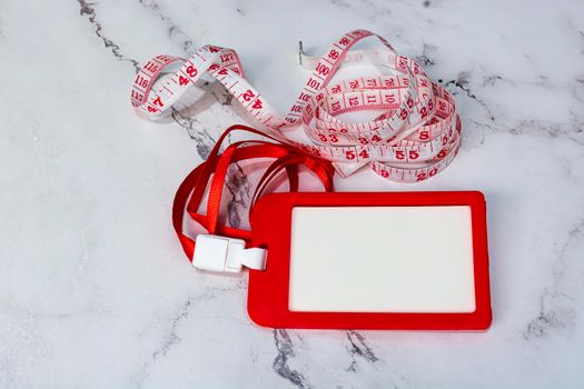 Red name tag with measure tap on white desk. Healthy and diet concept. Copy space. Flat lay.