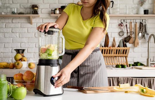 Preparing healthy foods. Healthy eating and dieting. Young brunette woman making banana smoothie at home kitchen