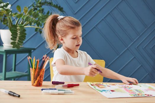 Creative process. Cute little girl in art school draws her first paintings by pencils and markers.