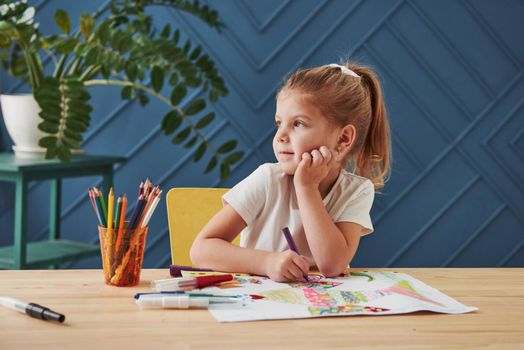 Having a rest. Cute little girl in art school draws her first paintings by pencils and markers.