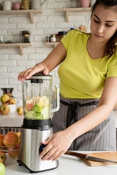 Preparing healthy foods. Healthy eating and dieting. Young brunette woman making banana smoothie at home kitchen