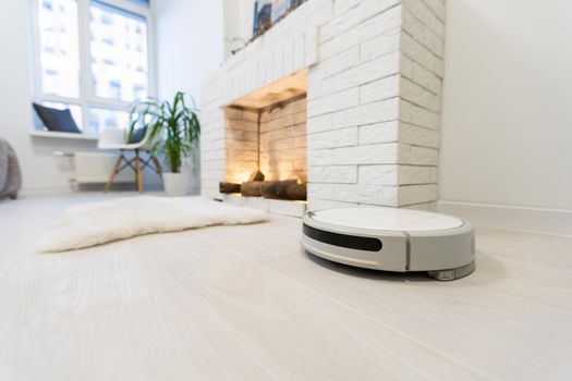 Smart House. Vacuum cleaner robot runs on wood floor in a living room.