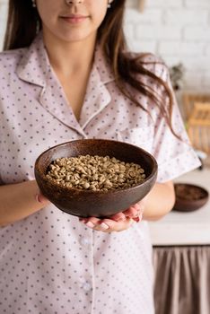 Alternative coffee brewing. young woman in lovely pajamas making coffee at home kitchen holding bowl with coffee beans