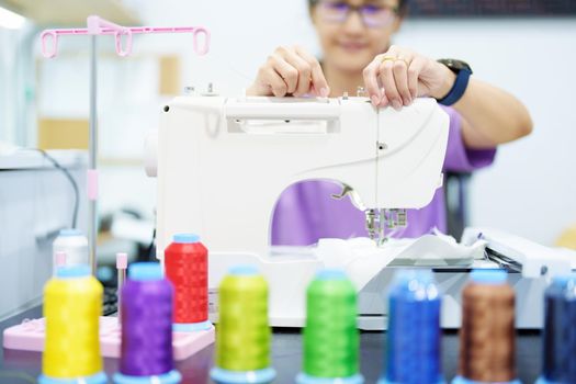 Embroidery, handicrafts, SME, family business Portrait of an Asian female designer picking up sewing threads for Design patterns using automatic embroidery machines according to customer orders