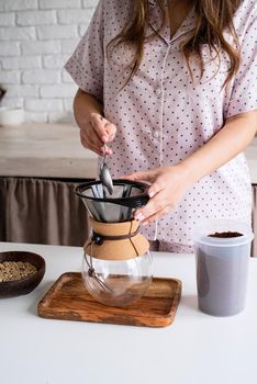 Alternative coffee brewing. young woman in lovely pajamas making coffee at home kitchen