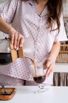 Alternative coffee brewing. young woman in lovely pajamas making coffee at home kitchen