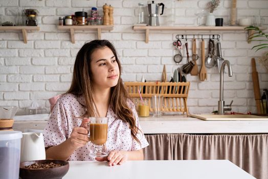 Alternative coffee brewing. young woman in lovely pajamas drinking coffee with milk at home kitchen