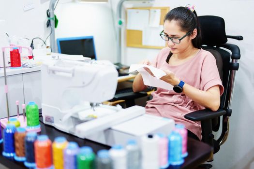 Embroidery, handicrafts, hobbies, SME business, family business, Portrait of Asian female designers are doing by designing patterns using automatic embroidery machines by customer order