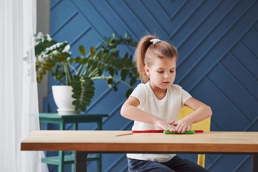 Children playing with colored plasticine on the wooden table at home.