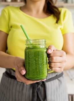 Healthy eating, dieting concept. Close up of a young woman holding a jar of green smoothie