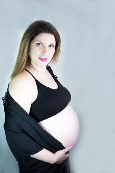 Eight month pregnant woman with bare belly. Happy emotion