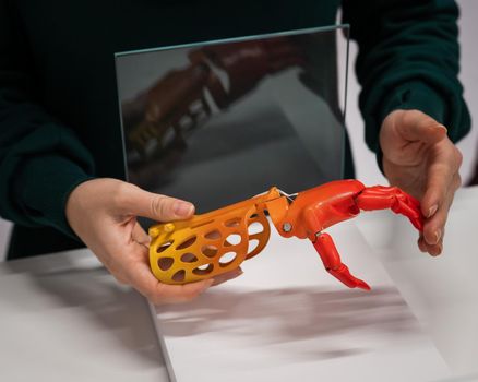 A woman demonstrates a plastic children's prosthetic hand printed on a 3D printer