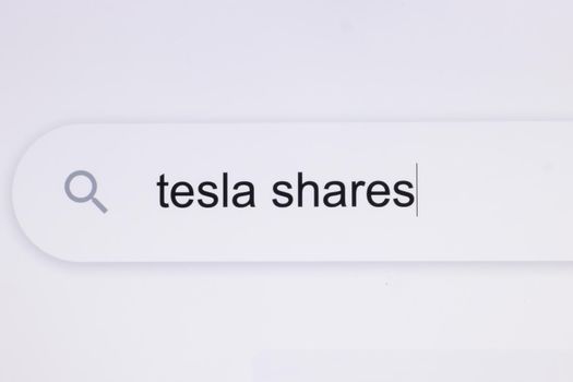 Typing the word Tesla shares in the browser on a pixelated screen. Searching For an Online Network Website. Searching The World Wide Web Internet on a Computer.