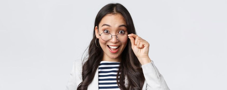 Business, finance and employment, female successful entrepreneurs concept. Excited happy asian office worker take-off glasses and smiling astonished as receive awesome deal.