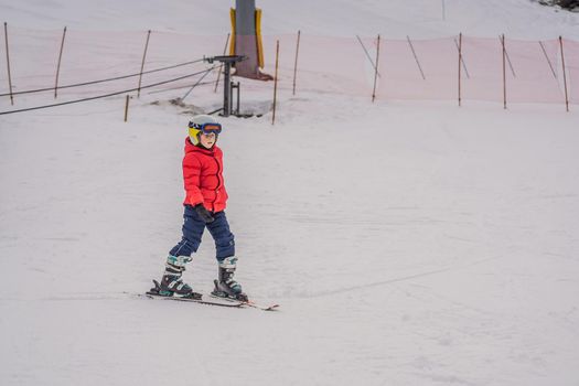 Child skiing in mountains. Active toddler kid with safety helmet, goggles and poles. Ski race for young children. Winter sport for family. Kids ski lesson in alpine school. Little skier racing in snow.