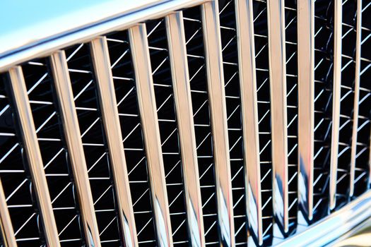 Grid of car with sunflare. Radiator grille. Metal close-up texture background. Chrome grill of big powerful engine macro.