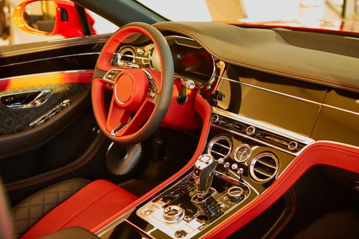 Red luxury car Interior. Steering wheel, shift lever and dashboard. Shallow doff.