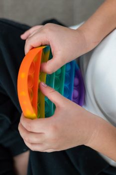 Faceless little boy playing pop it rainbow colors