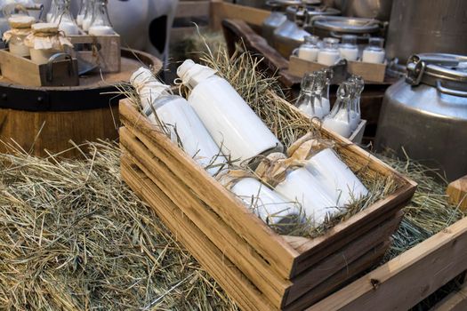 Milk - decoration on farm. Agriculture, farming. Farmer milk in bottles. Natural milk, organic milk. Vintage ornament with hay, straw and bottles with yogurt. Farmer product. Rustic decor. Products