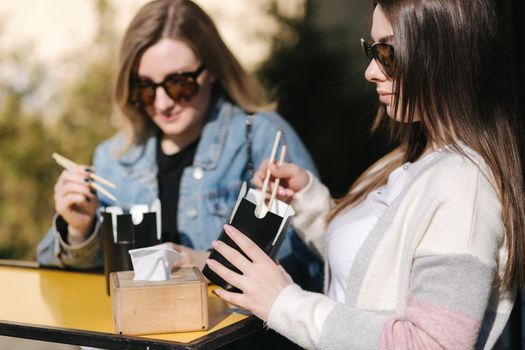 Delitious lunch of takeaway asian food outdoors. Best friends spend time together in pring sunny day.