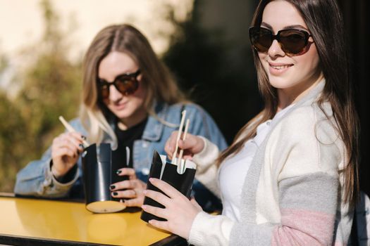 Delitious lunch of takeaway asian food outdoors. Best friends spend time together in pring sunny day.