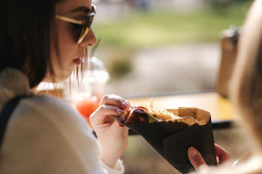 Tasty hot-dog in female's hands. Girls buy street food.