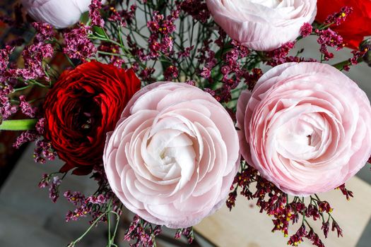 Bouquet of red and pink Persian buttercups on a white table. Scandinavian style. Place for text