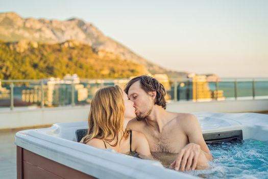 Portrait of young carefree happy smiling couple relaxing at hot tub during enjoying happy traveling moment vacation life against the background of green big mountains.