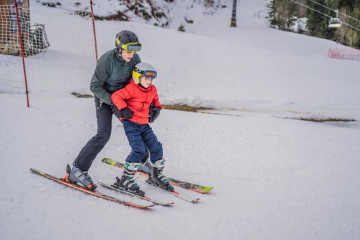 Boy learning to ski, training and listening to his ski instructor on the slope in winter.