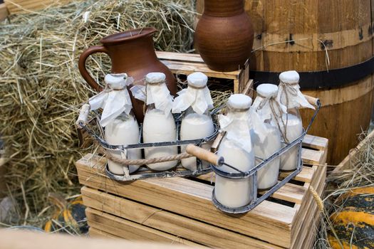 Milk - decoration on farm. Agriculture, farming. Farmer milk in bottles. Natural milk, organic milk. Vintage ornament with hay, straw and bottles with yogurt. Farmer product. Rustic decor. Products