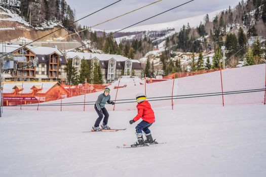 Boy learning to ski, training and listening to his ski instructor on the slope in winter.