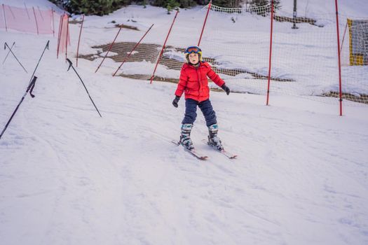 Child skiing in mountains. Active toddler kid with safety helmet, goggles and poles. Ski race for young children. Winter sport for family. Kids ski lesson in alpine school. Little skier racing in snow.