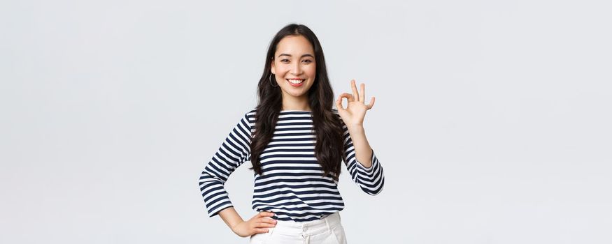 Lifestyle, beauty and fashion, people emotions concept. Satisfied good-looking female guarantee quality of product, recommend advertisement, showing okay sign, say no problem, all good.