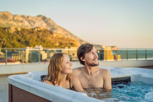 Portrait of young carefree happy smiling couple relaxing at hot tub during enjoying happy traveling moment vacation life against the background of green big mountains.