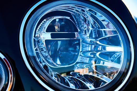 Headlight detail of luxury car. Closeup of sedan headlamp. Car headlight background