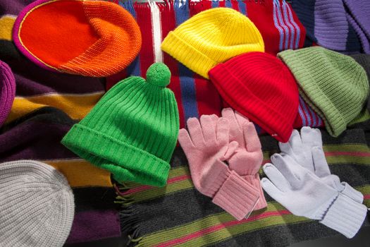 Multicolored knitted and crocheted hats, scarves, gloves are laid out on the counter as decoration